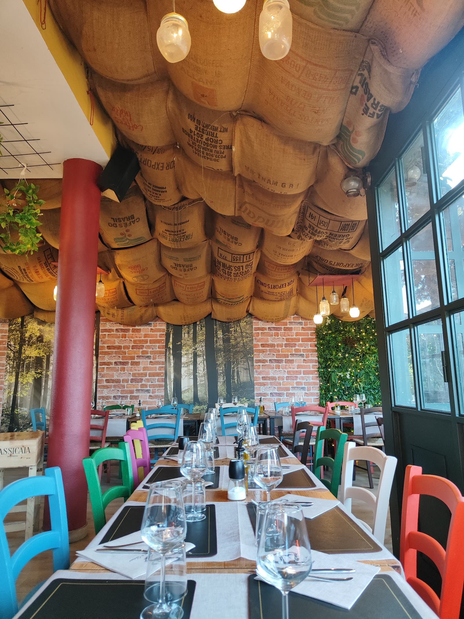 La sala dell'Osteria Pane e Salame apparecchiata, tra mattoni a vista e lampade calde